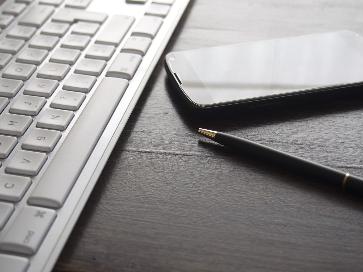 Keyboard, smartphone and pen on a dark desk